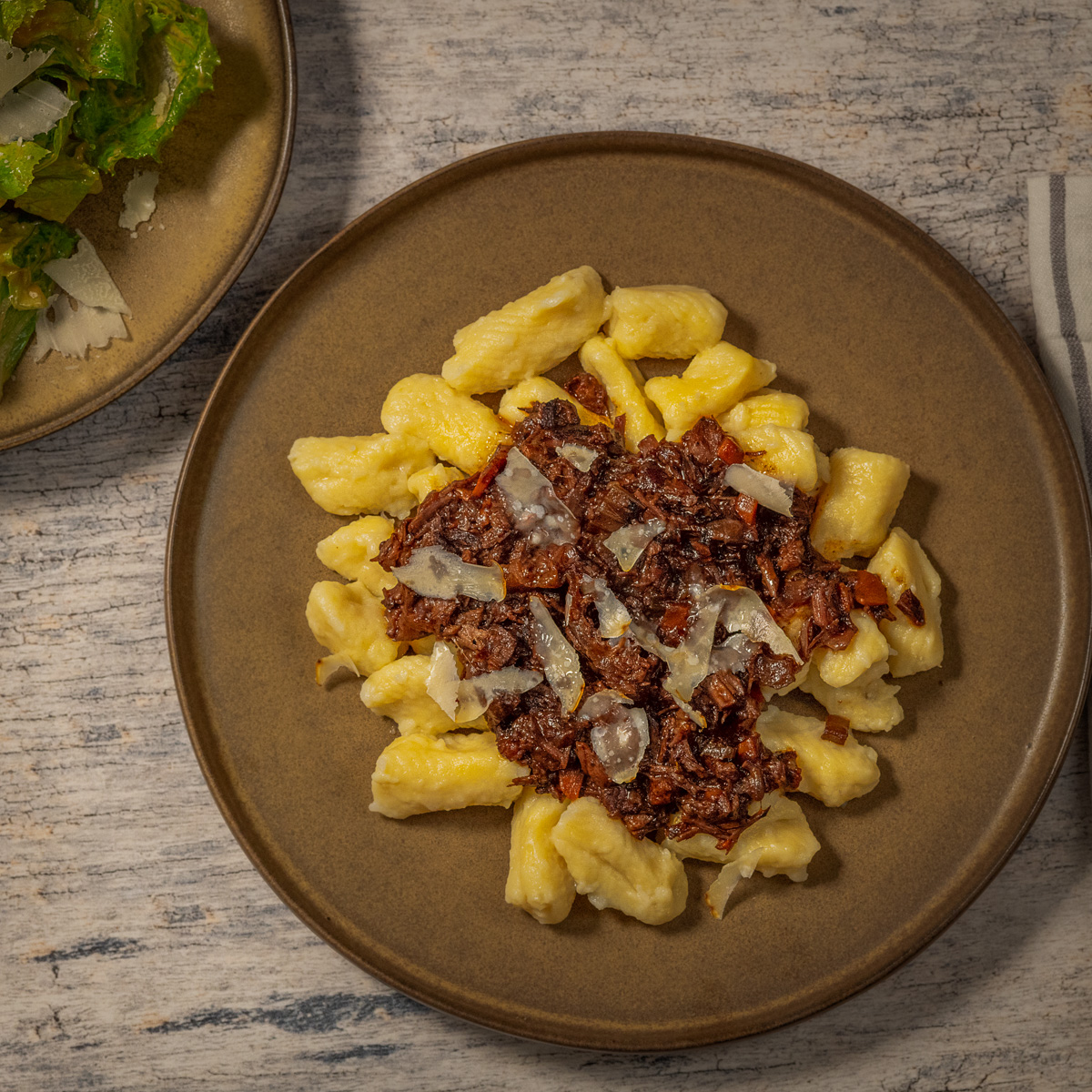 Plate of gnocchi with short rib ragu and shave parmesan cheese.