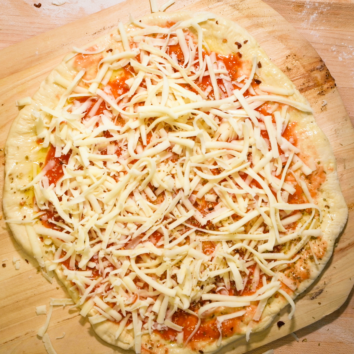 Add cheese on top of pizza sauce.