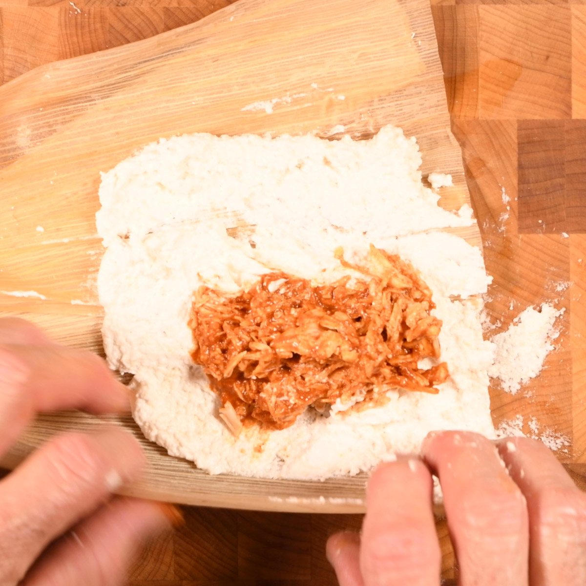 Add a scoop of chicken and birria sauce and fold the tamale.