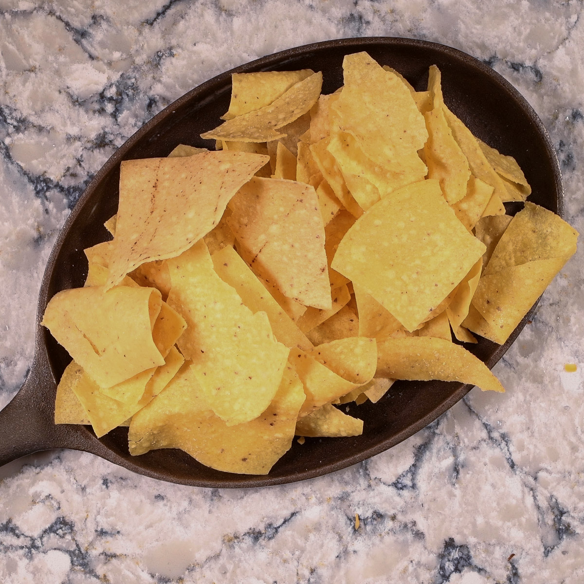 Spread a layer of tortilla chips on an oven safe pan.