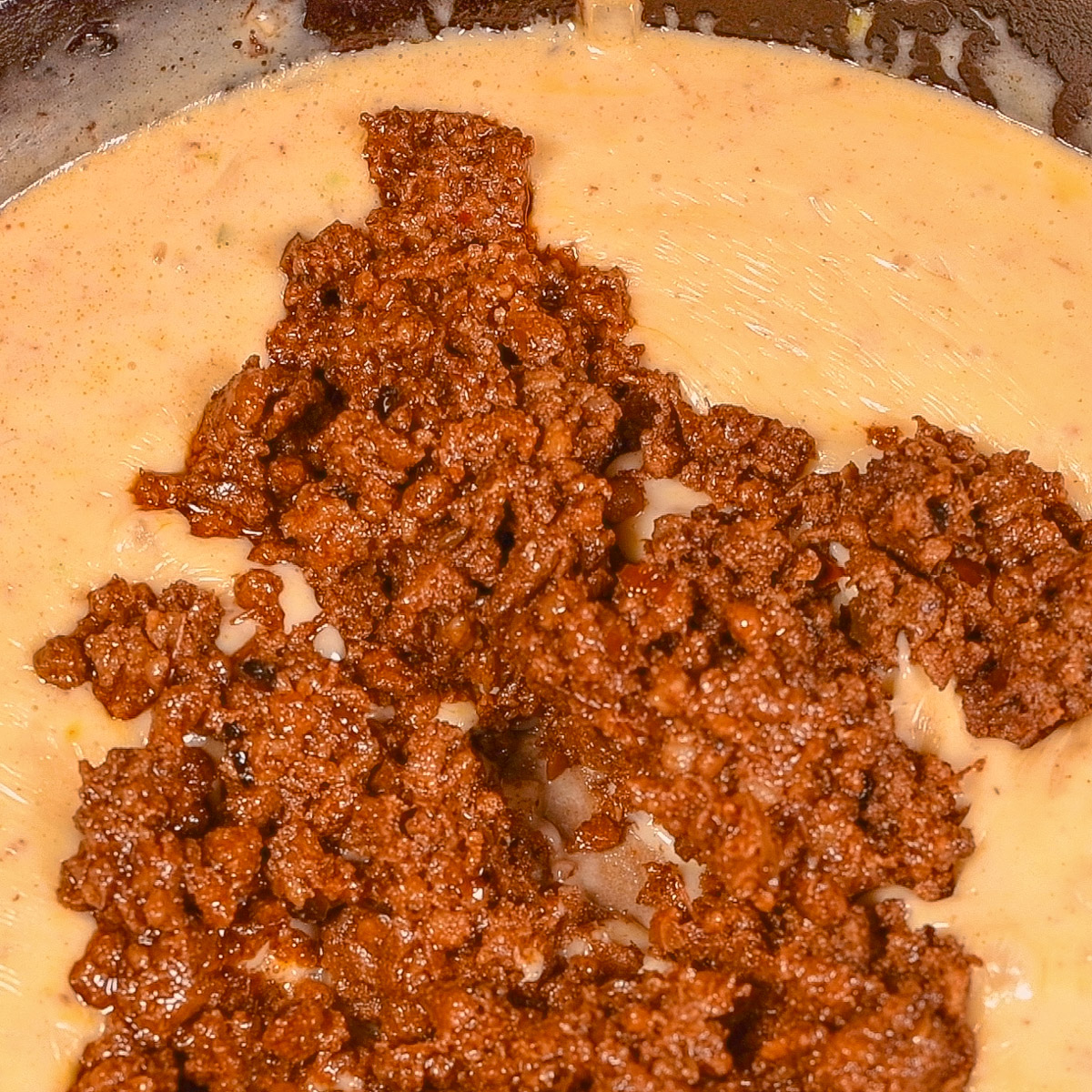 Add the cooked chorizo to the melted cheese mixture and stir to combine.