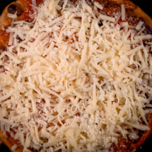 Add more sauce and cheese to the pizza dough.