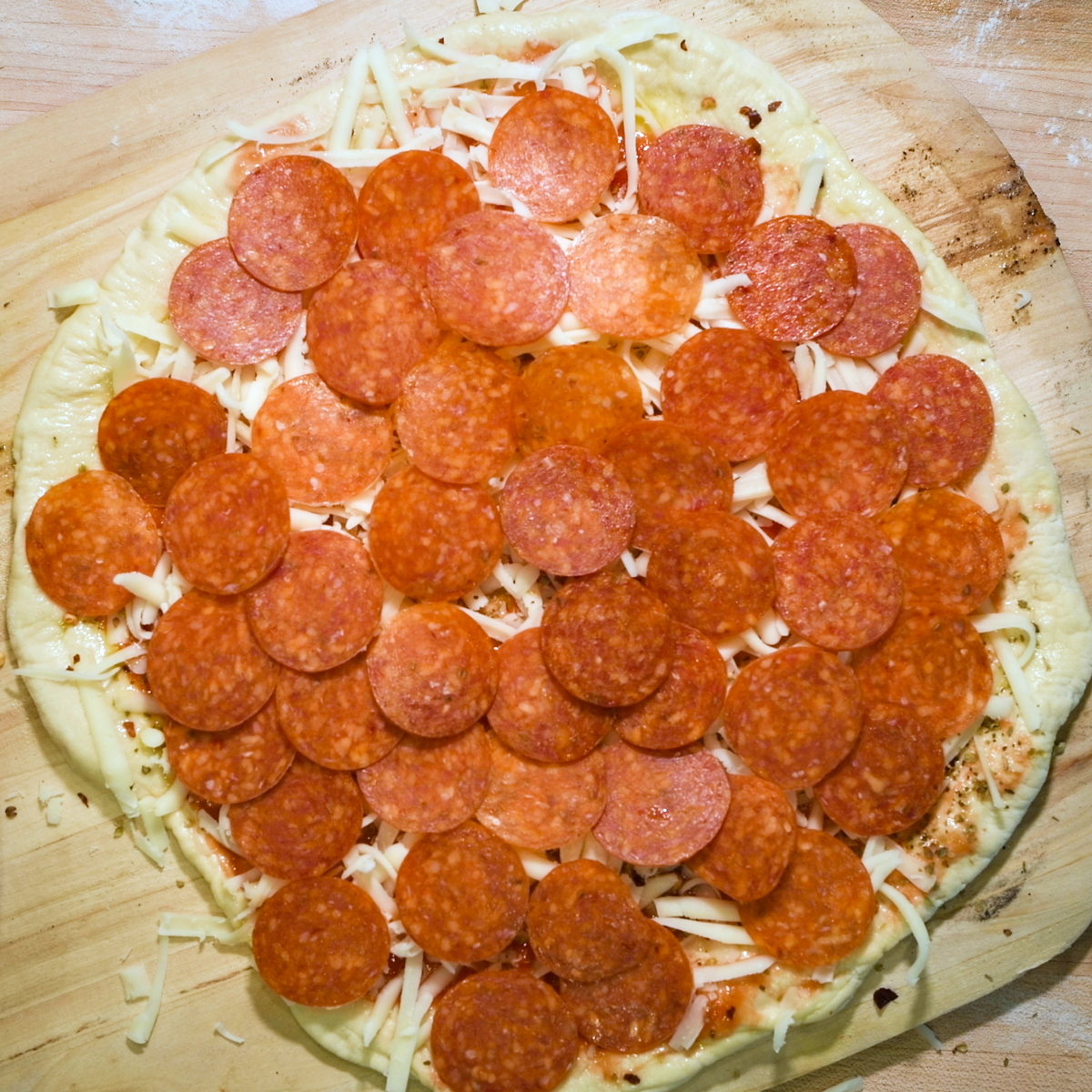 Spread sliced pepperoni on top of cheese.