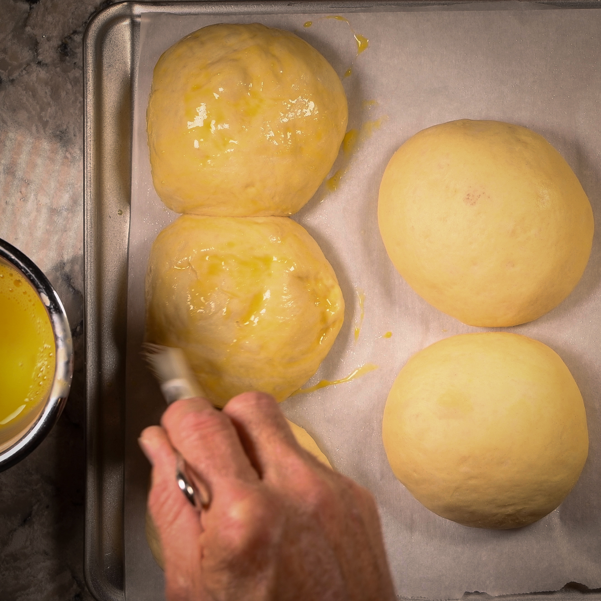 Brush the tops of the brioche buns with egg wash.