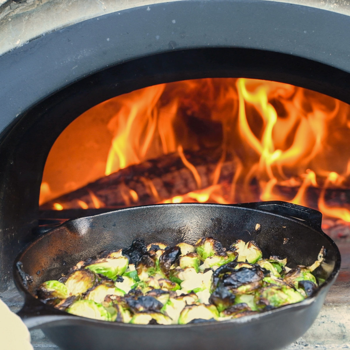 Brussels sprouts roasting in a wood-fired oven.
