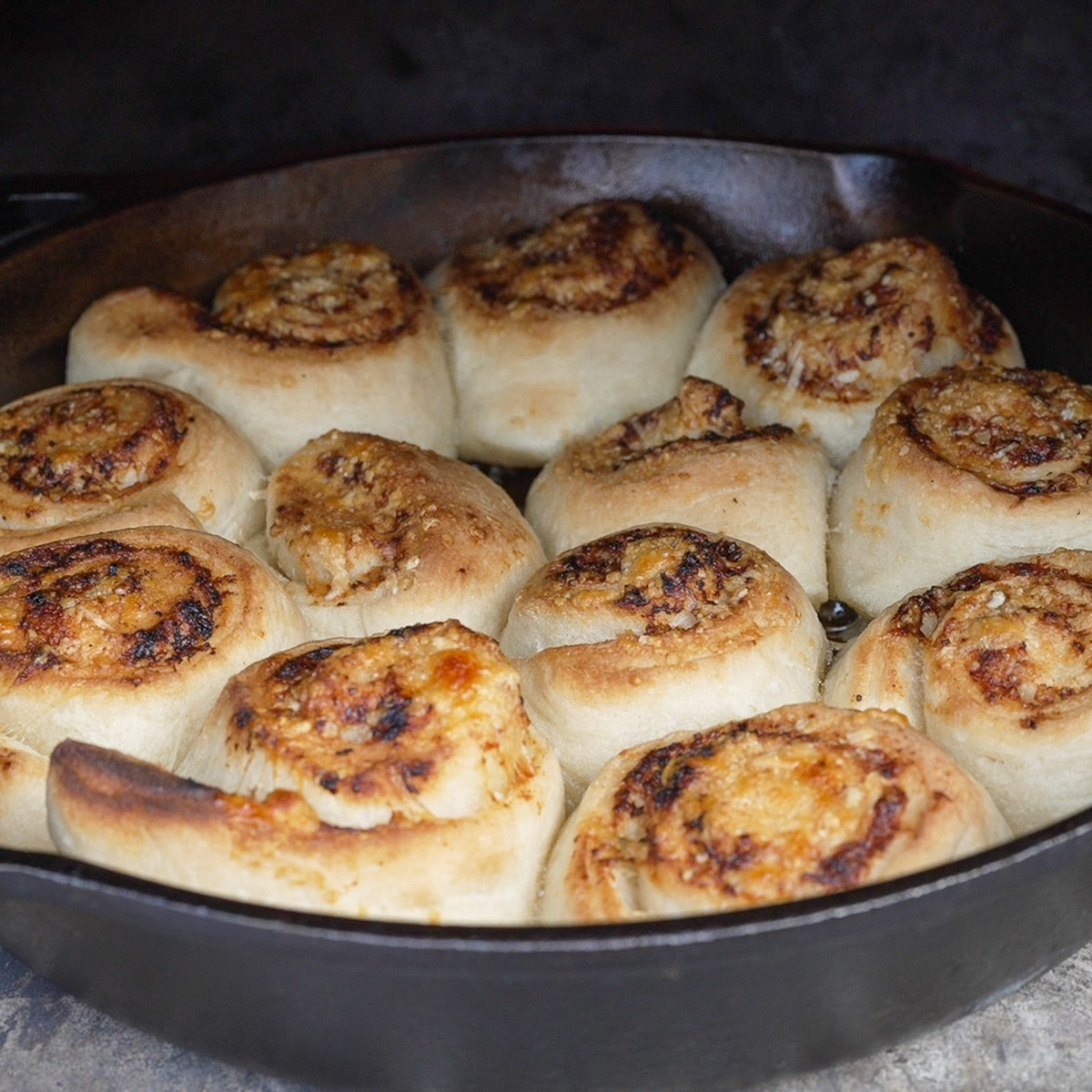 Cheesy garlic rolls coming out of a wood-fired oven.
