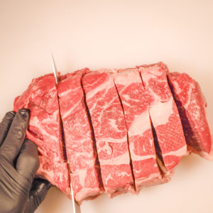 Chuck roast being cut into cubes.