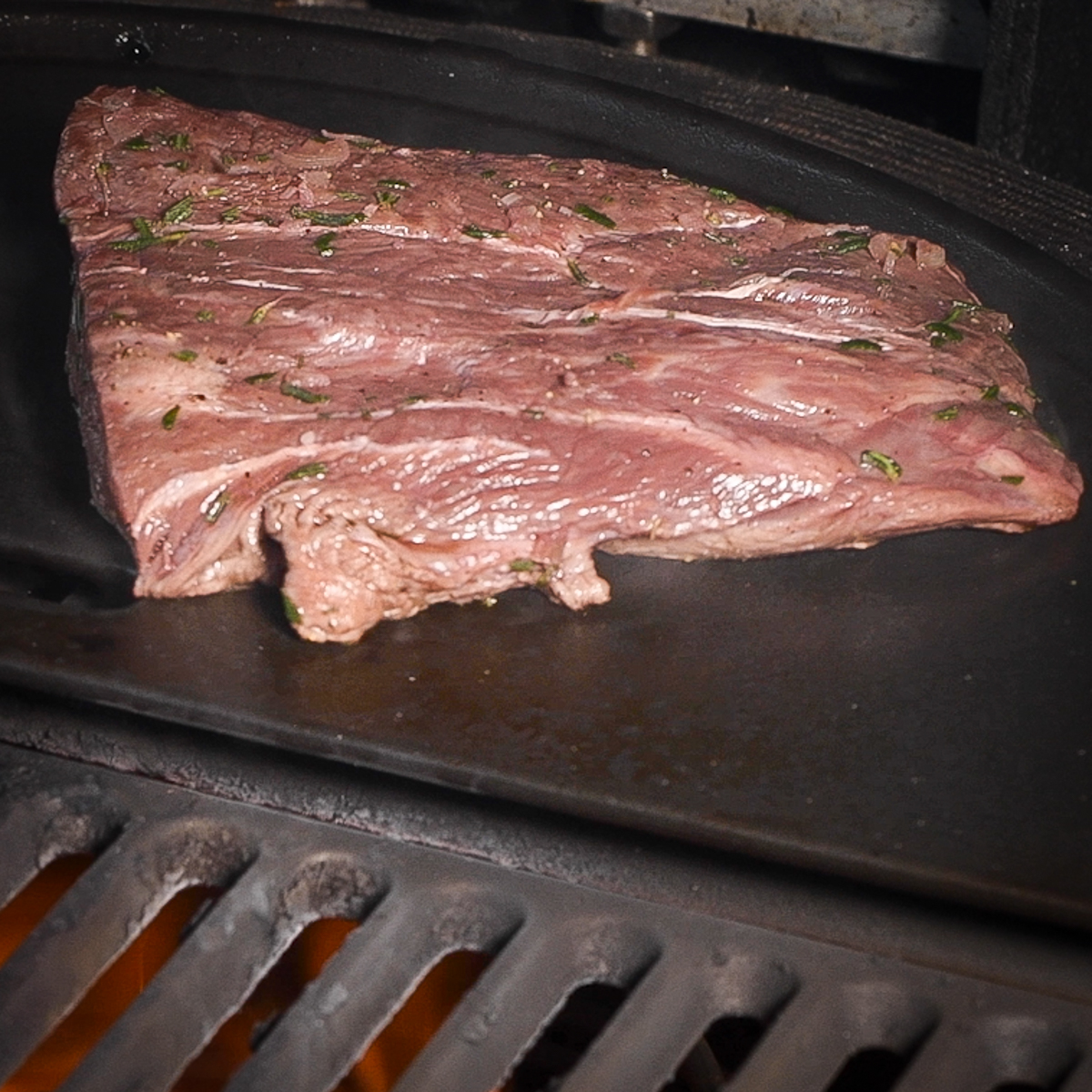 Raw flat iron steak on hot griddle.