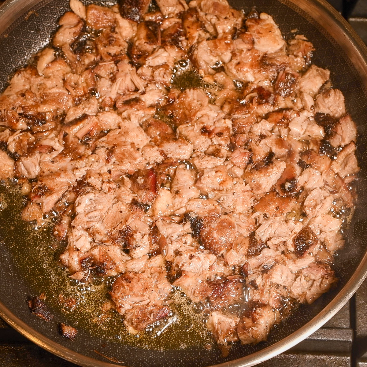 Sear the carnitas meat in a skillet over medium-high heat.
