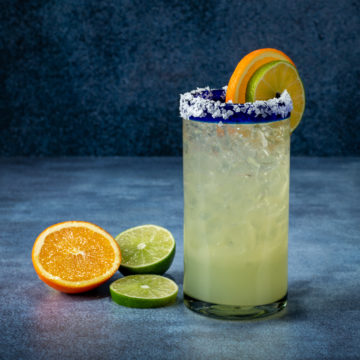 Margarita with a salted rim and slices of orange and lime.