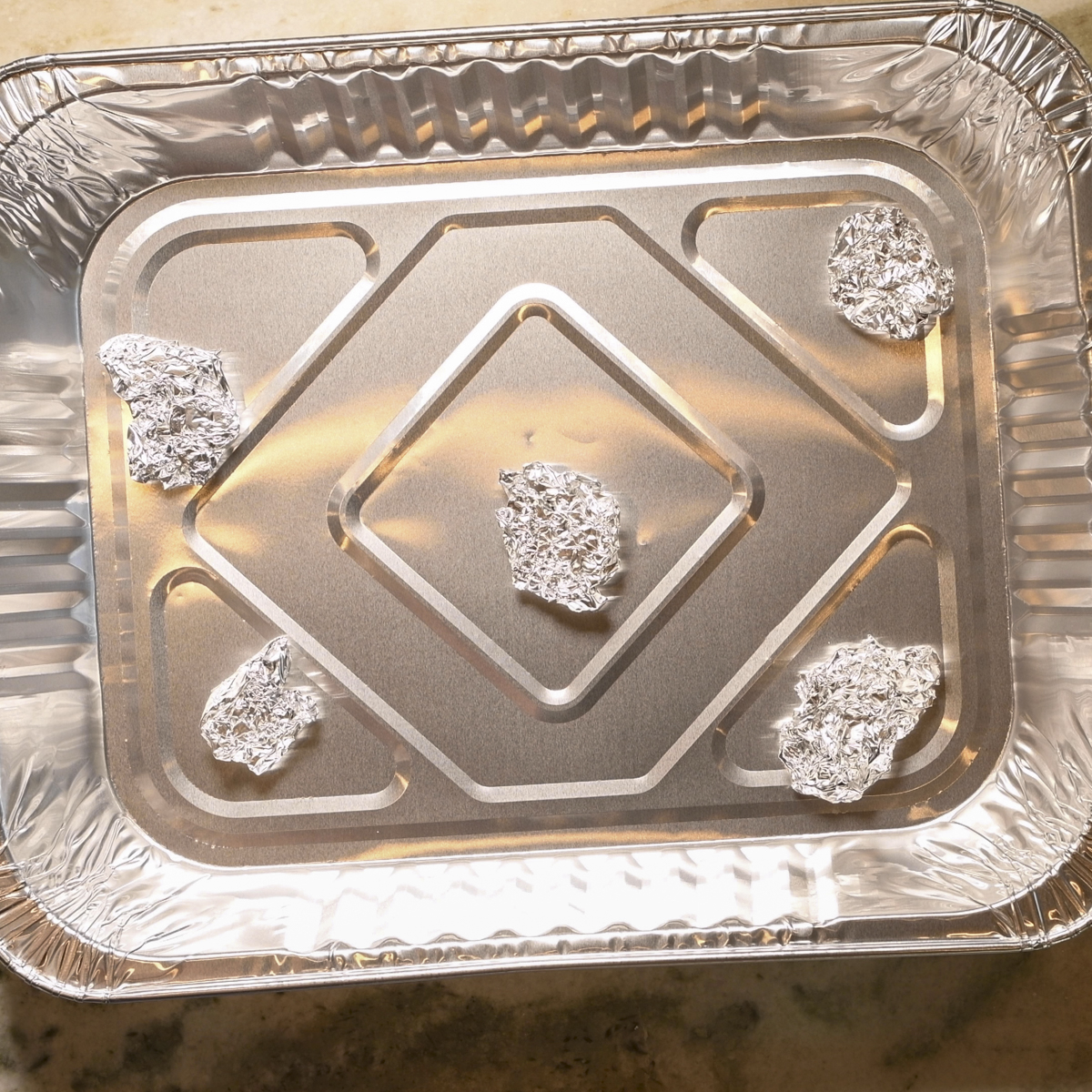 Place wads of foil in the bottom of another pan to elevate the pan with the holes.