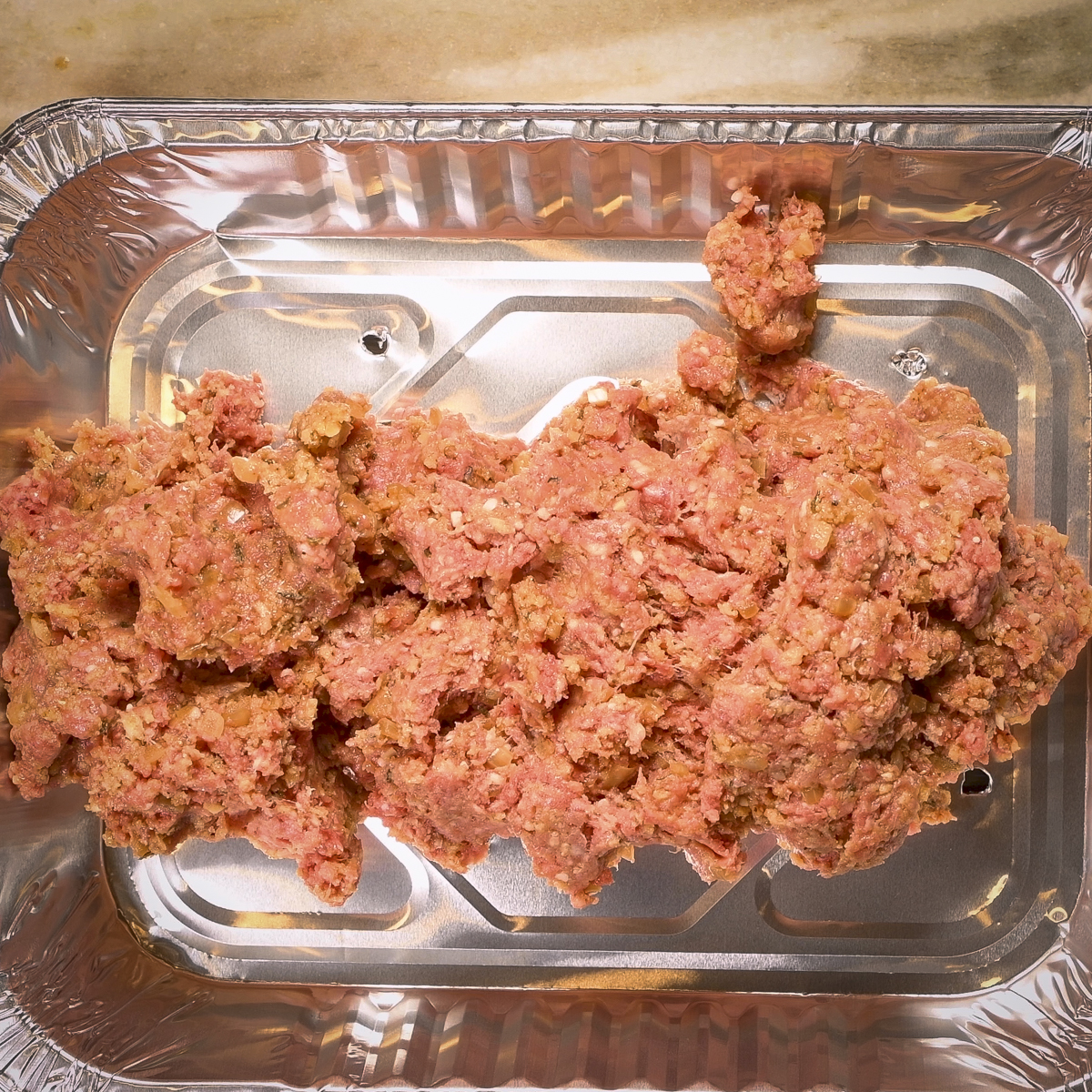 Transfer the meat mixture to the prepared aluminum pan.