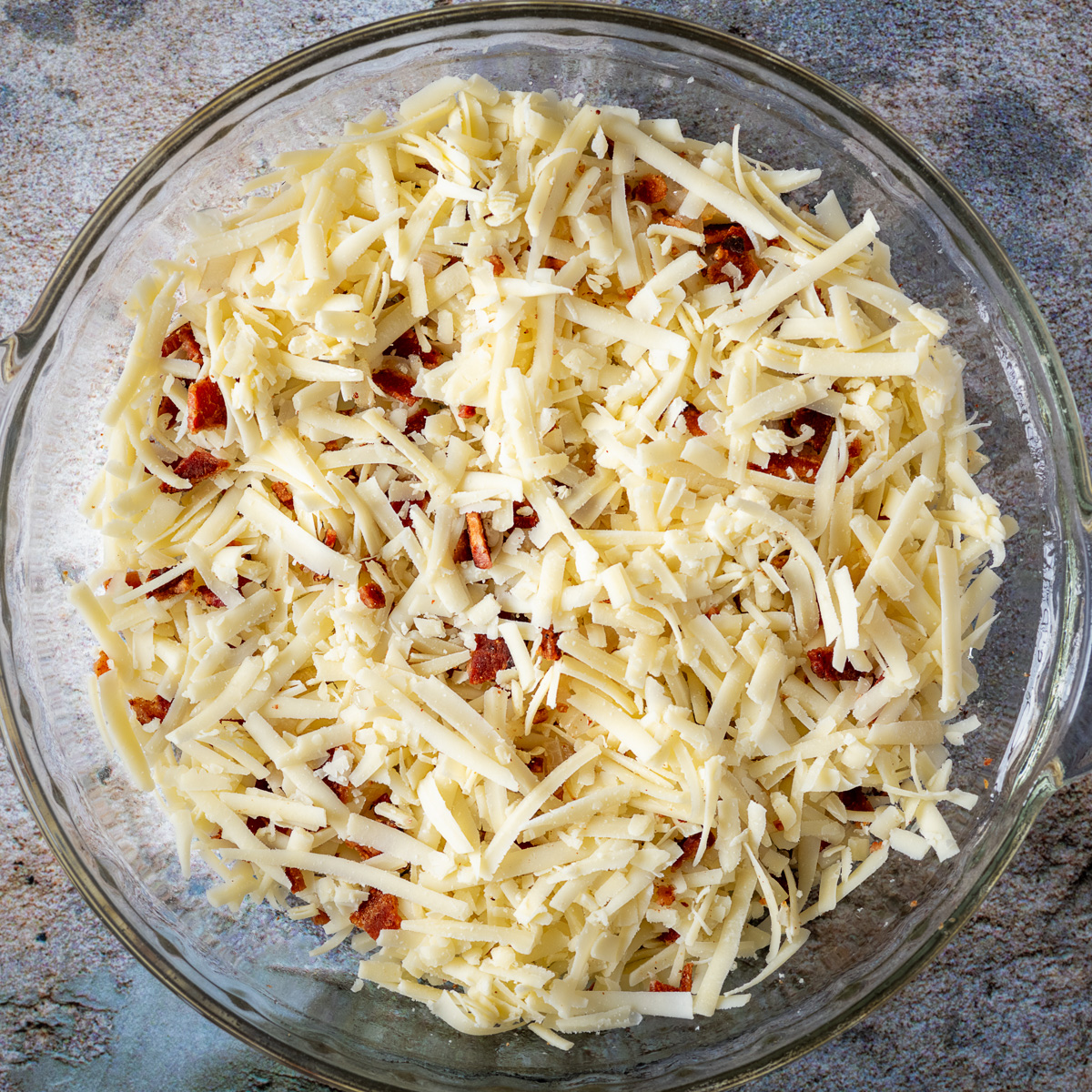 Add additional layers of bacon, onion and cheese to pie dish.
