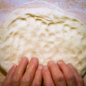 Flatten pizza dough into a disc.