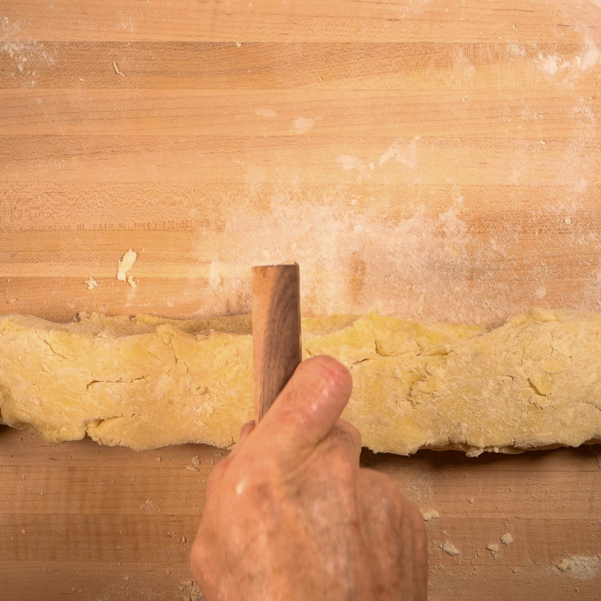 Roll the potato dough into a log and cut into four pieces.