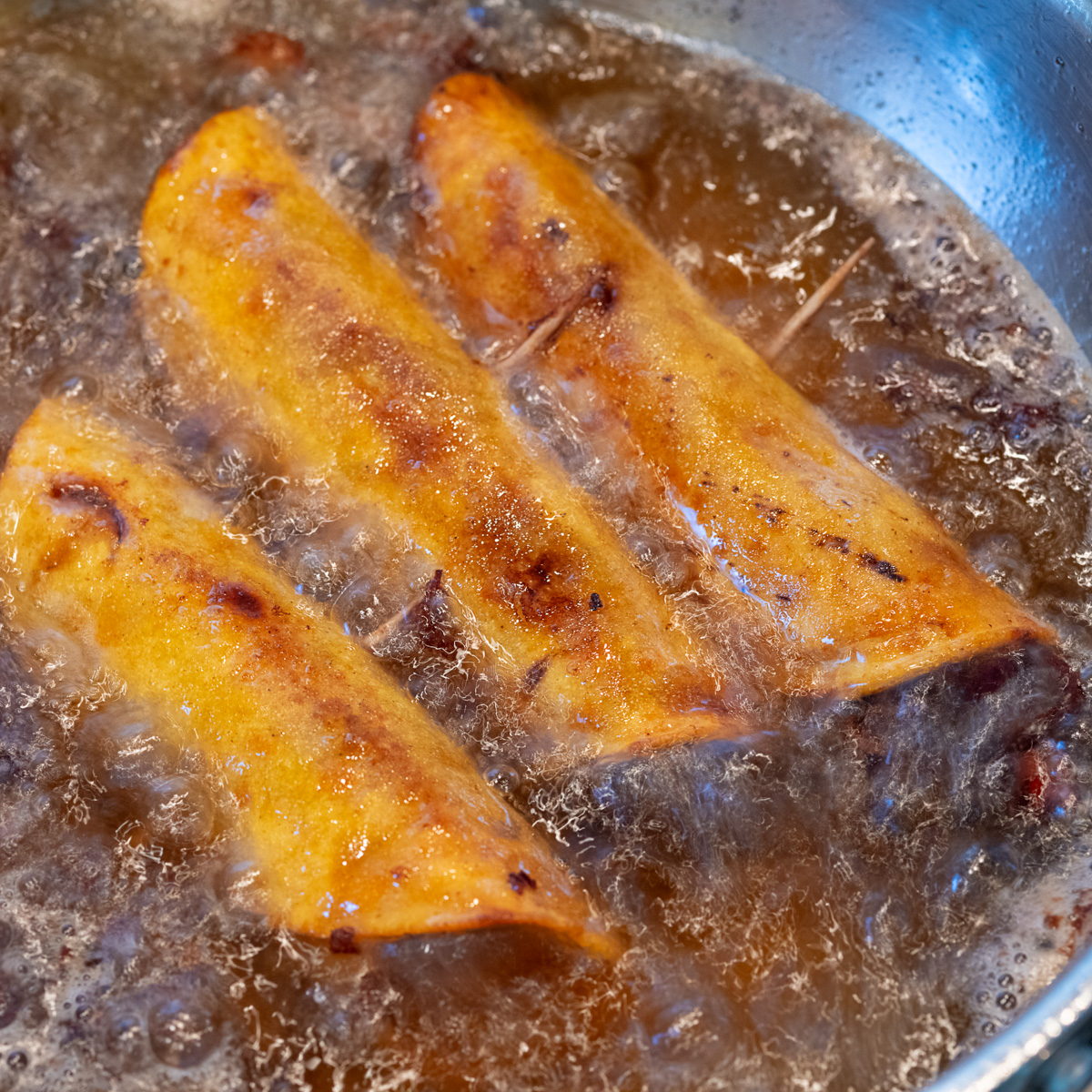 Brisket taquitos in a fryer.