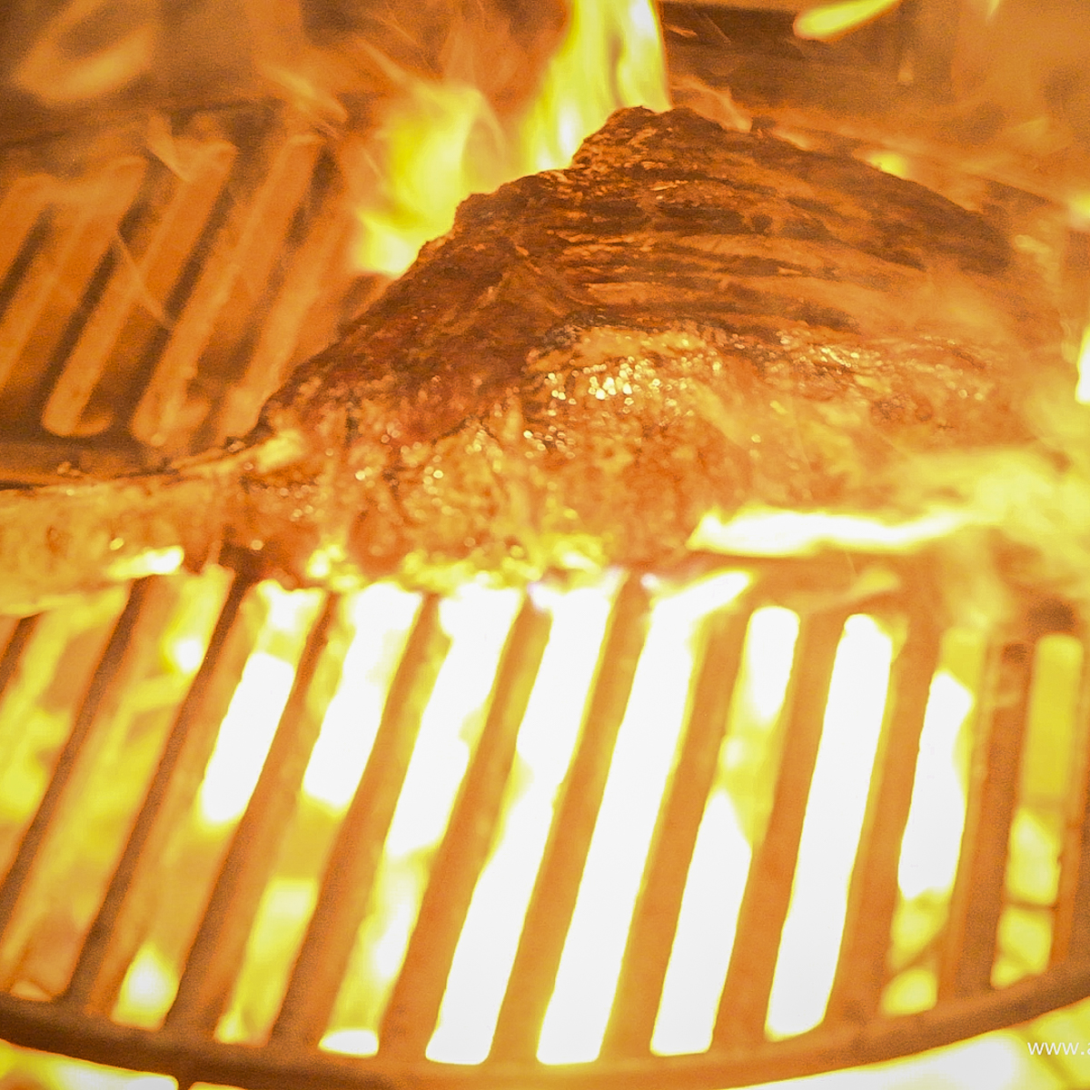 Tomahawk steak being seared over high heat.