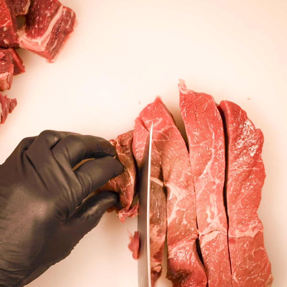 Top sirloin being cut into cubes.