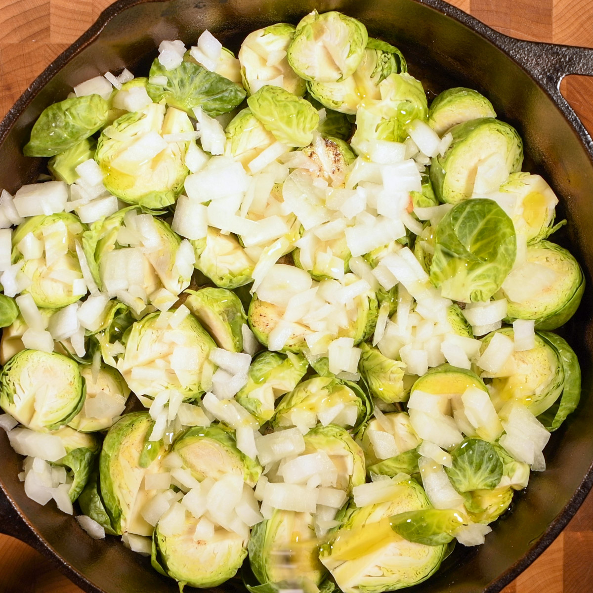 Trimmed Brussels sprouts and onion in a cast iron skillet.